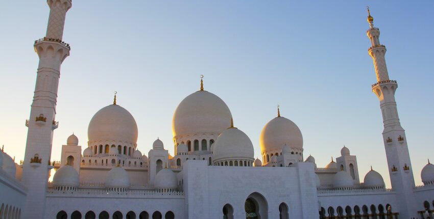Mosquée blanche avec dômes et minarets au coucher du soleil.