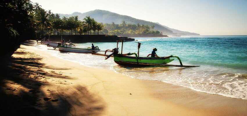 Plage tropicale avec bateaux et palmiers.