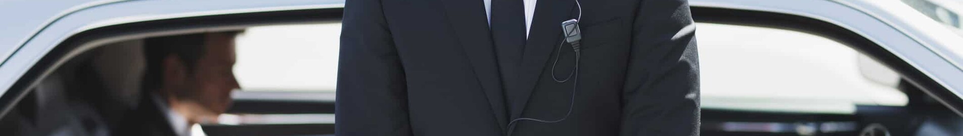 Homme en costume devant voiture – service de sécurité.