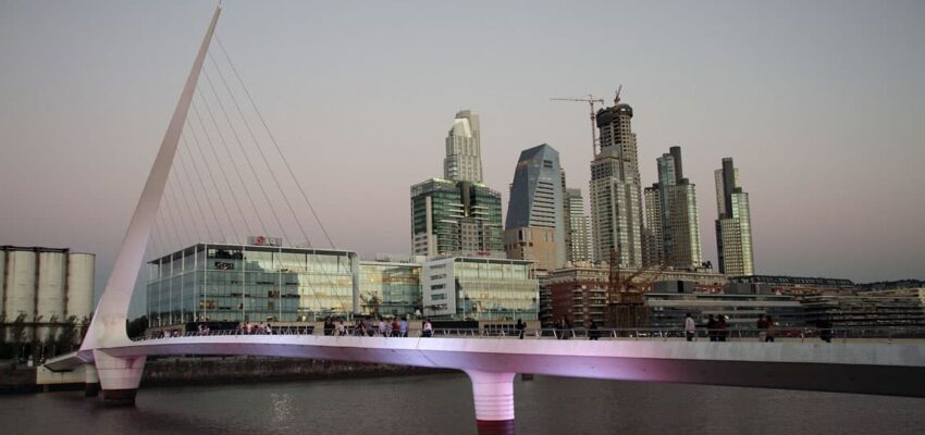 Pont blanc moderne sur l'eau avec skyline en arrière-plan.