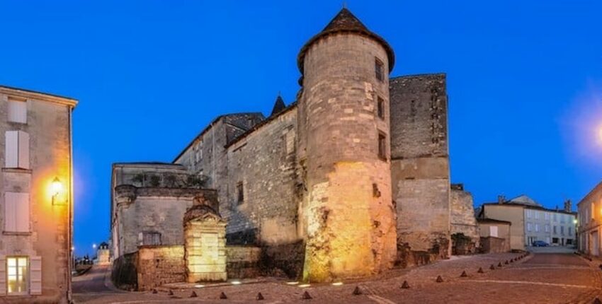 Cognac Châteaubernard fort et tour ronde illuminée au crépuscule.