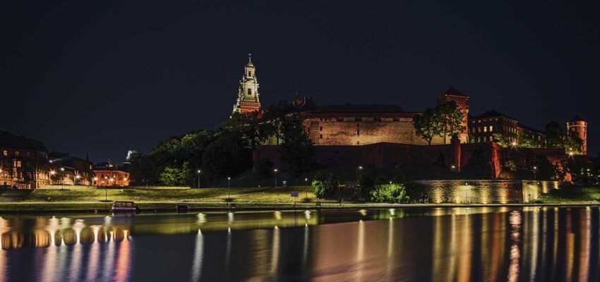 Château au bord de la rivière reflété sur l'eau calme la nuit.