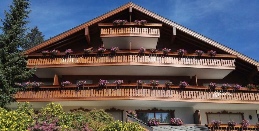 Chalet alpin avec balcons fleuris, ciel bleu clair.
