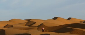 Motocycliste dans le désert près de Dakar, ciel bleu.