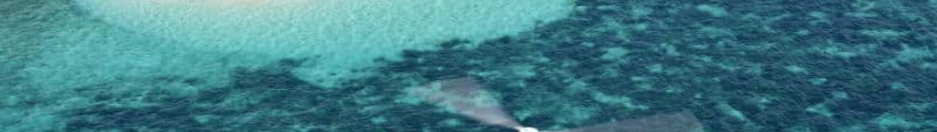 Location jet privé, hélicoptères survolant île sableuse et eau turquoise.