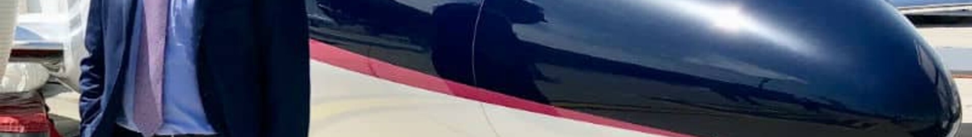 location de jet privé : homme en costume à côté d'un avion.