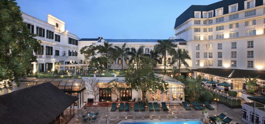 Hôtel luxueux avec piscine et palmiers.