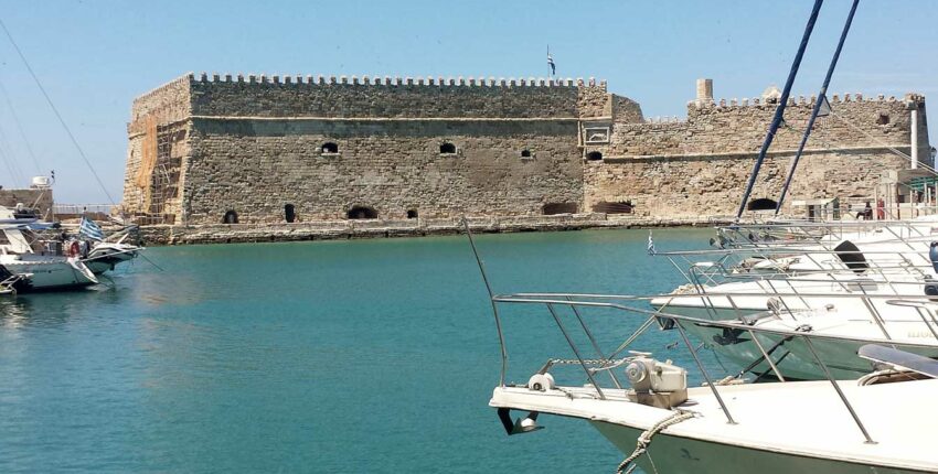 forteresse historique, eau turquoise, bateaux blancs sous ciel bleu.
