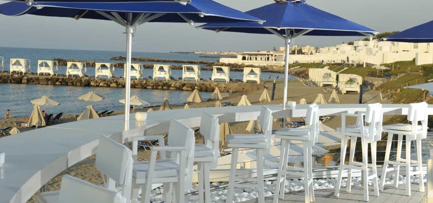Bar front de mer : chaises blanches, parasols bleus, plage