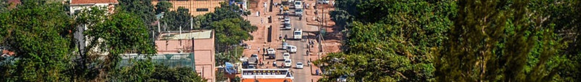 Rue animée de Kampala avec collines et ciel dégagé.