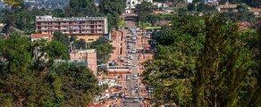 Rue animée de Kampala avec collines et ciel dégagé.