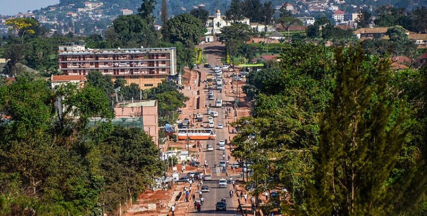 Rue animée de Kampala avec collines et ciel dégagé.