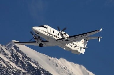 Location jet privé : Avion survole montagnes enneigées.