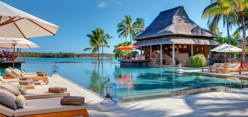 Resort tropical : piscine, transats, pavillon, palmiers.