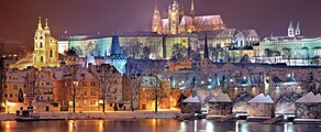 Vue nocturne sur ville enneigée avec château illuminé.