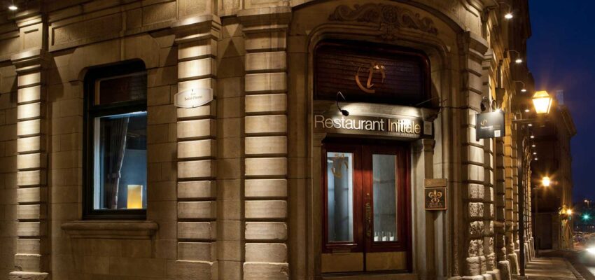 Entrée restaurant gastronomique nocturne, façade éclairée.