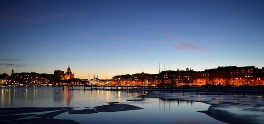 Helsinki crépuscule : Front de mer serein, immeubles illuminés.