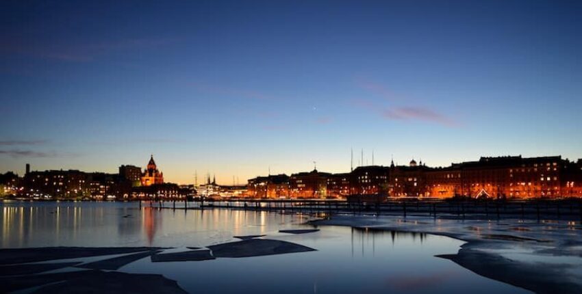 Helsinki crépuscule : Front de mer serein, immeubles illuminés.