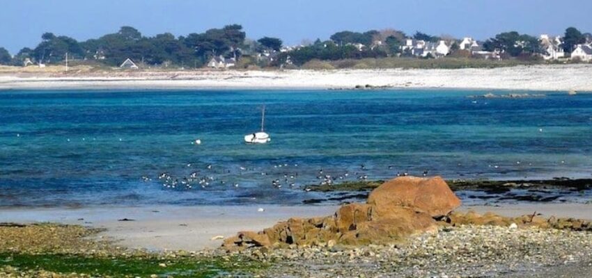 Plage rocheuse, bateau amarré, eau turquoise près de Lannion.