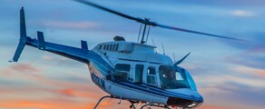 Hélicoptère Bell 206 en vol avec couché de soleil