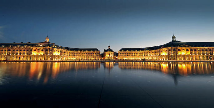 Monument éclairé reflétant sur l'eau à Bordeaux, France
