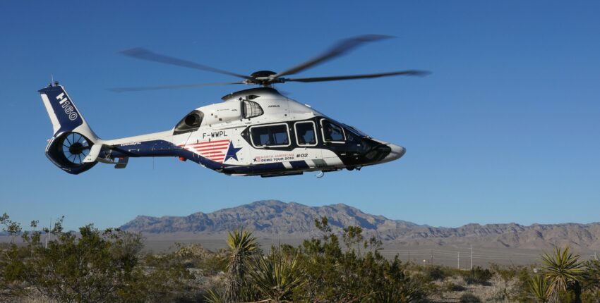 location jet privé : Hélicoptère blanc et bleu dans le désert.