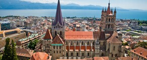 Vue aérienne Cathédrale de Lausanne, toits rouges, lac, montagnes.