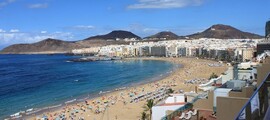 Las Palmas Gran Canaria plage bondée, eau bleue, montagnes.