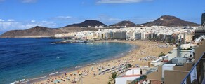 Las Palmas Gran Canaria plage bondée, eau bleue, montagnes.
