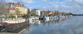 Vue panoramique Roanne, rivière calme, bateaux à quai, journée ensoleillée.