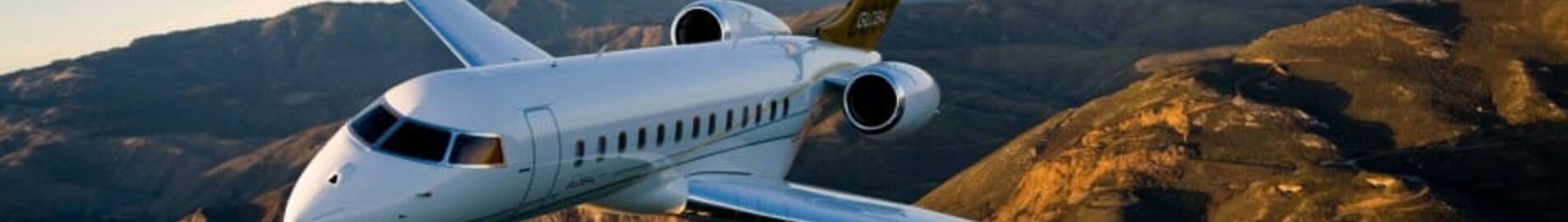 Le jet privé Bombardier Global 6000 en vol avec un couché de soleil, la mer et des montages
