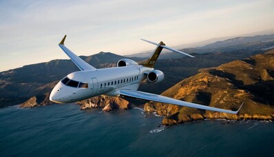Le jet privé Bombardier Global 6000 en vol avec un couché de soleil, la mer et des montages