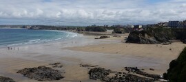Plage Newquay, Cornouailles avec falaises rocheuses et bâtiments.
