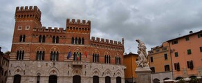 Grosseto, bâtiment historique avec statue et drapeaux.