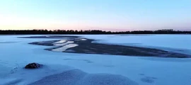 Vaxjo Urasa : lac enneigé, ciel clair, arbres.