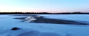 Vaxjo Urasa : lac enneigé, ciel clair, arbres.