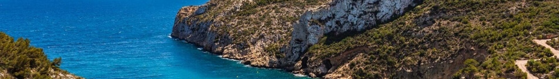 Plage isolée en Espagne entourée de falaises et de verdure.