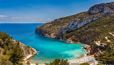 Plage isolée en Espagne entourée de falaises et de verdure.