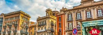 Ambiance espagnole : Place animée et bâtiments historiques vibrants.