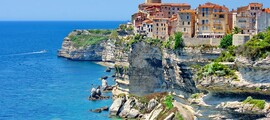 **Texte alternatif :** Corse : Ville colorée, mer bleue, et bateau en-dessous.