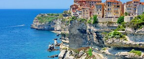 **Texte alternatif :** Corse : Ville colorée, mer bleue, et bateau en-dessous.