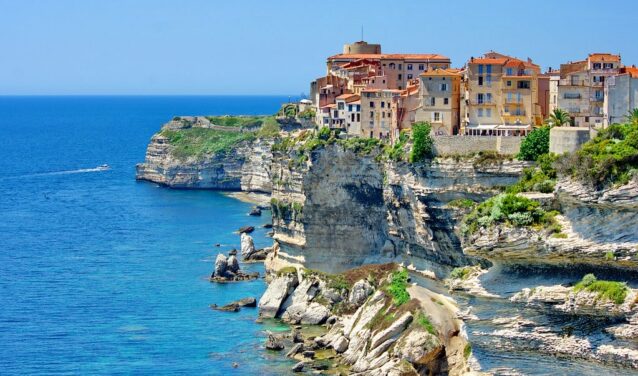 **Texte alternatif :** Corse : Ville colorée, mer bleue, et bateau en-dessous.