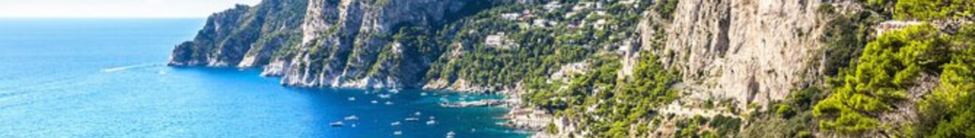 Capri entourée par des bateaux sur mer bleue.
