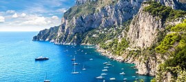 Capri entourée par des bateaux sur mer bleue.