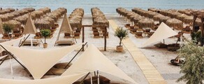 Une plage à Mamaia, des parasols beiges et l'océan.
