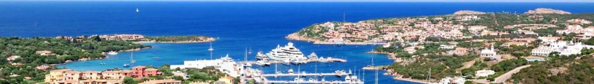 Marina de Porto Cervo, collines vertes et océan en arrière-plan.