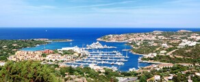 Marina de Porto Cervo, collines vertes et océan en arrière-plan.