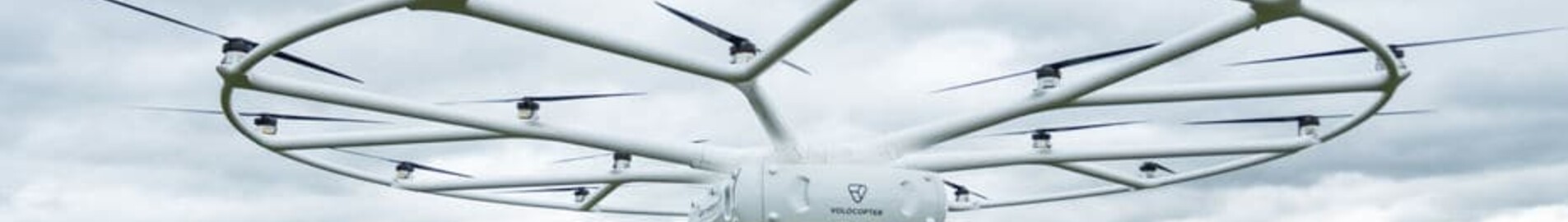 VOLODRONE survolant un champ herbeux sous ciel nuageux.