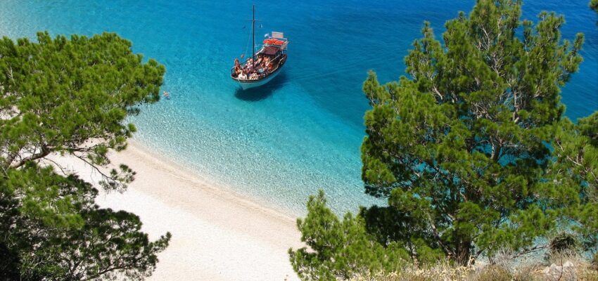 location de jet privé : Plage sereine, bateau rustique abordant l'île